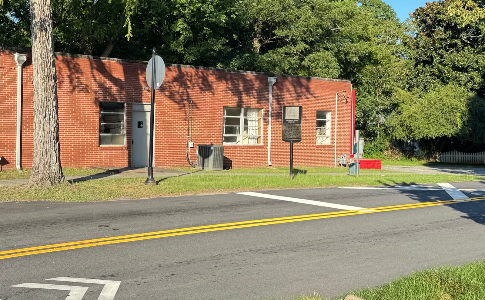 The former post office on the Brunswick site: a low flat-roofed brick building with the historic marker on the lawn in front of it