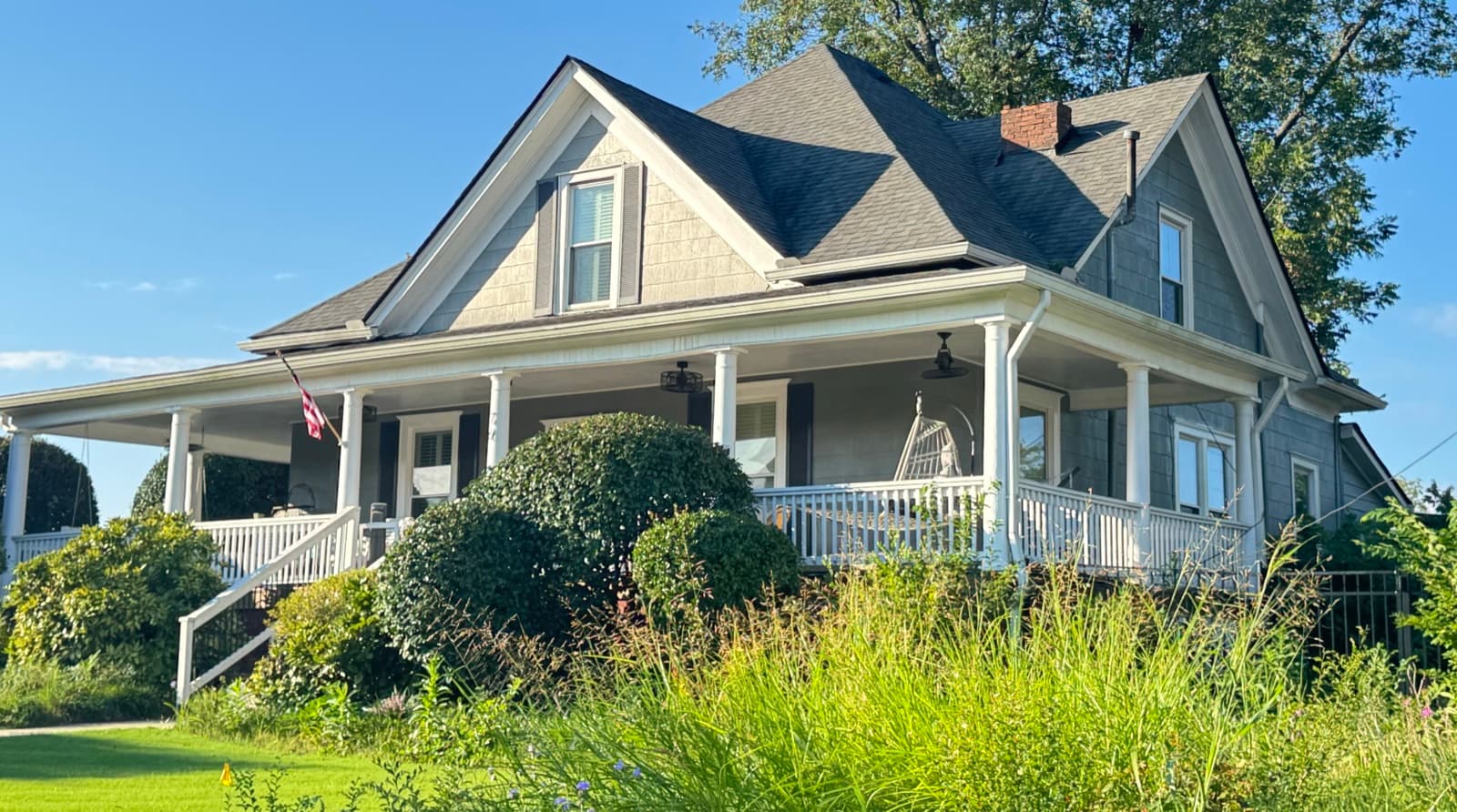 The 1908 house on the north corner of Thrasher Commons before conversion, with a wraparound porch and overgrown front garden